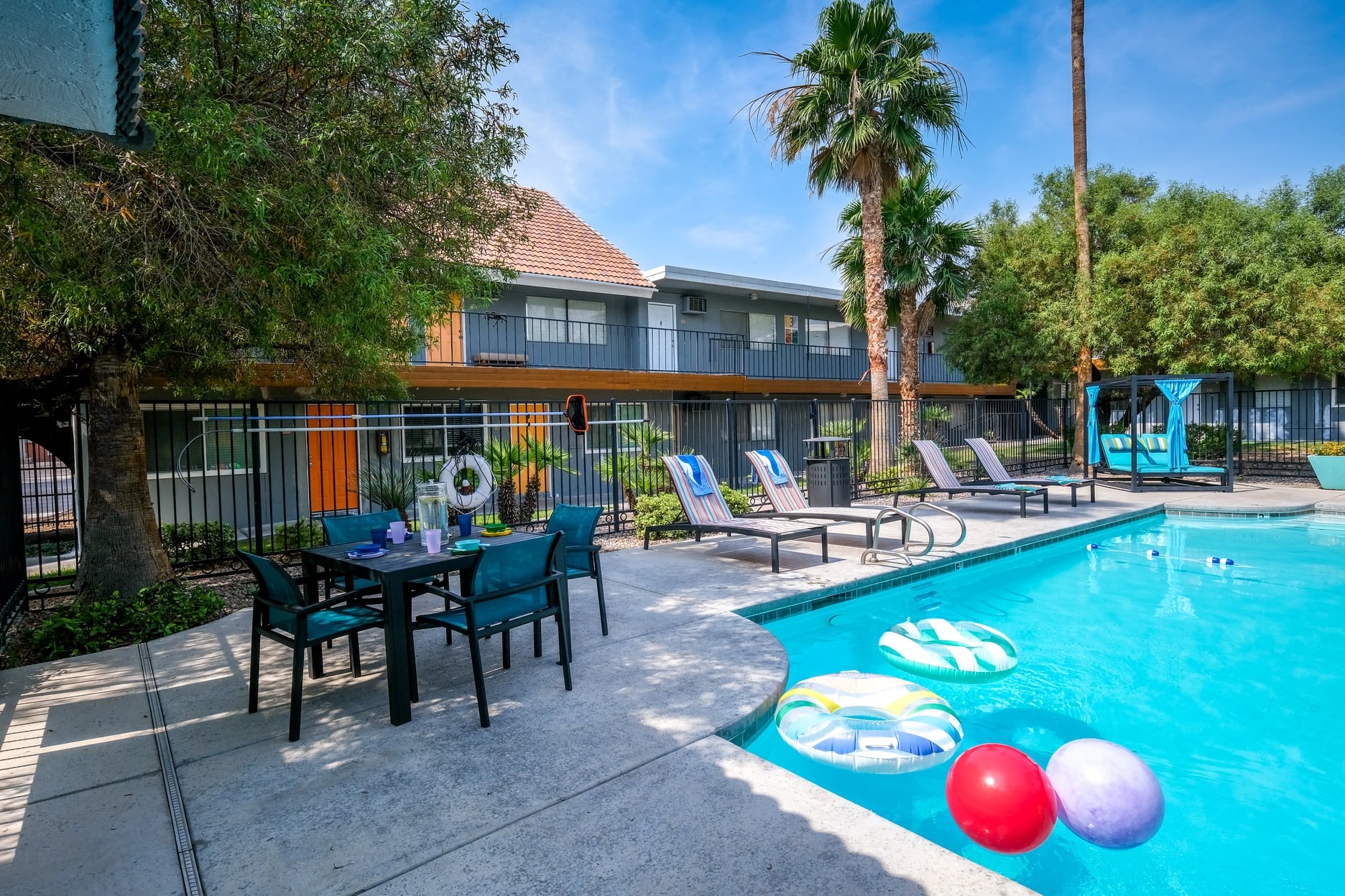 Community pool at fifteen 50 apartments in Las Vegas, NV, 89119 with lounge chairs and patio umbrellas